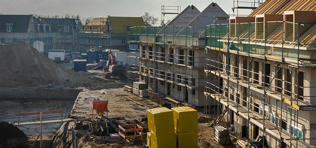 Neubaugebiet mit Baugrube und eingerüsteten halbfertiggestellten Neubauten – Symbolbild für eine Bauherrenhaftpflichtversicherung