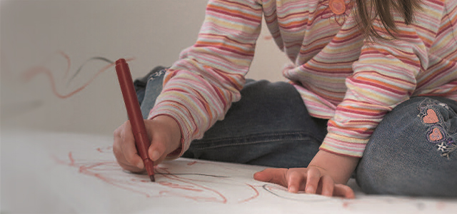 Ein Kleinkind bemalt mit einem Filzstift eine weiße Couch – Symbolbild für eine Privathaftpflichtversicherung