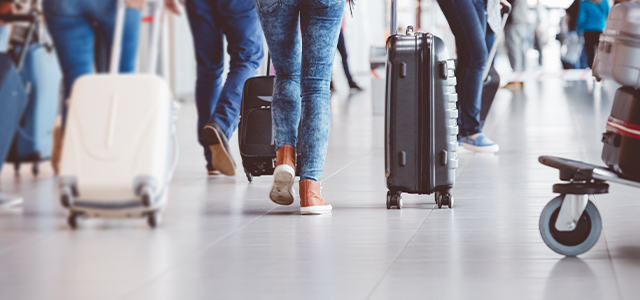 Reisende mit Gepäck am Flughafen – Symbolbild für Reiserücktrittversicherung