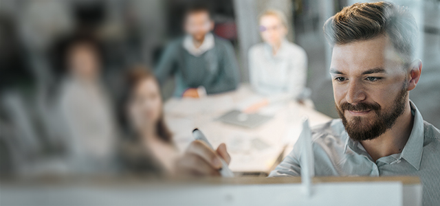 Mann schreibt vor einem Team mit vier Personen etwas an ein Whiteboard