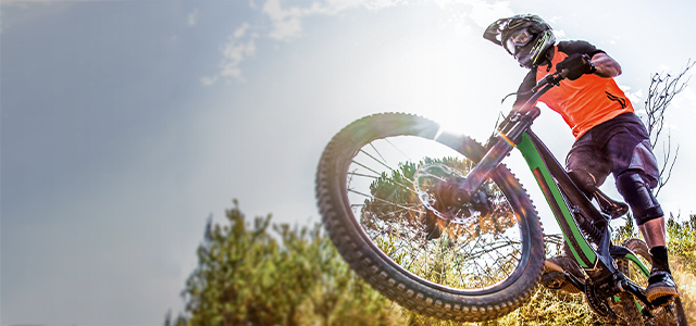 Ein Mann fährt mit Helm auf seinem Mountainbike einen Downhill Track hinunter