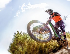 Ein Mann fährt mit Helm auf seinem Mountainbike einen Downhill Track hinunter